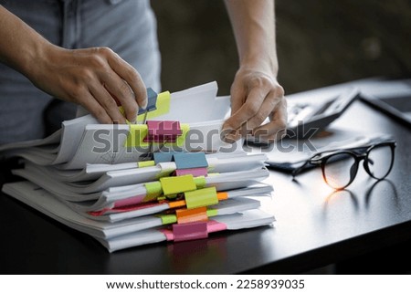 Businesswoman hands working in Stacks of paper files for searching and checking unfinished document achieves on folders papers Royalty-Free Stock Photo #2258939035