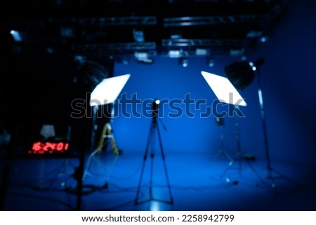 Blurred image of Professional video studio behind-the-scenes video footage behind silhouette production photography with a focus on camera and studio equipment.