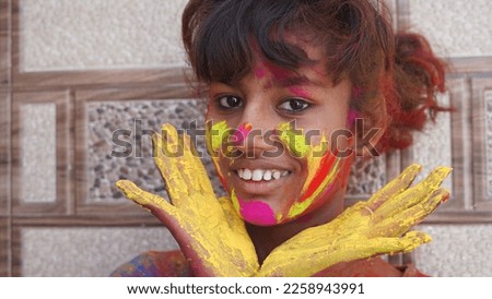Beautiful young girl posing with exploding pink and yellow Holi powder around her