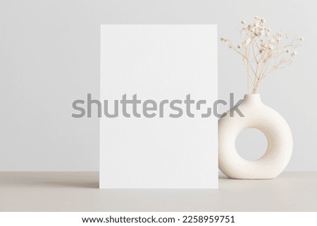 White invitation card mockup with a gypsophila on the beige table. 5x7 ratio, similar to A6, A5.