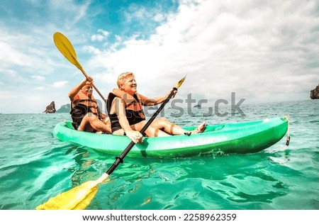 Happy retired couple enjoying travel moment paddling on kayak at Angthong marine park in Ko Samui in Thailand - Active elderly concept around world nature wonders - Bright vivid filtered tone Royalty-Free Stock Photo #2258962359