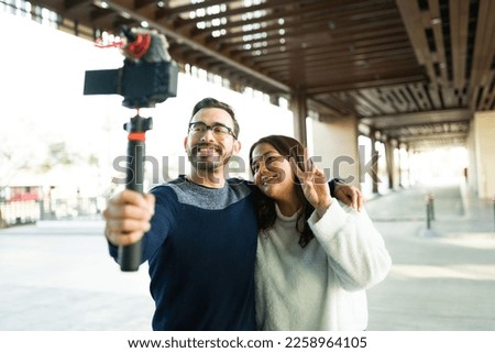 Happy beautiful influencer couple filming a video blog together for social media while around in the city