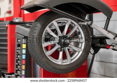 Wheel hanging on wheel balancer during car service inside of modern car dealer shop