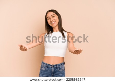 Young colombian woman isolated on beige background showing a welcome expression.
