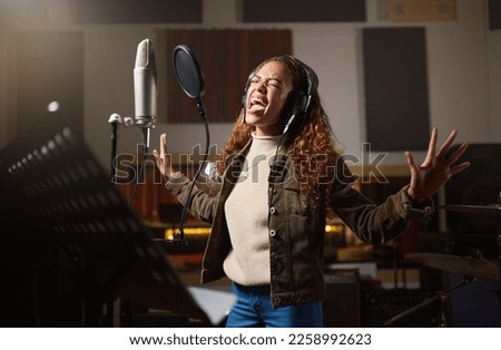 Music, streaming and woman recording in studio in home, singing into microphone with headphones and talent. Technology, art and creative influencer or musician with live stream song for record label. Royalty-Free Stock Photo #2258992623