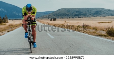 Full length portrait of an active triathlete in sportswear and with a protective helmet riding a bicycle. Selective focus  Royalty-Free Stock Photo #2258995871