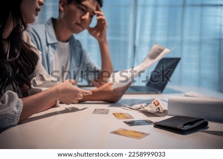 Asian young depressed couple having argument while checking money debt. Attractive new marriage man and woman looking frustrated to paperwork and bill, feel worried about financial problem in house. Royalty-Free Stock Photo #2258999033