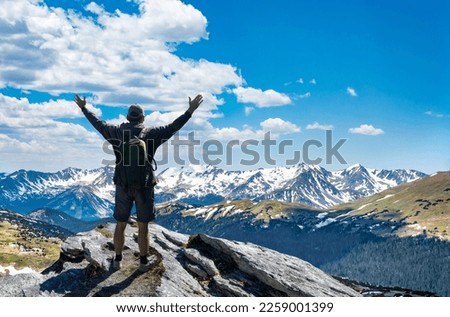 Hiker with arms up standing on the top of the mountain - Successful man enjoying triumph - Sport and success concept. Rocky Mountains National Park, Colorado, USA. Royalty-Free Stock Photo #2259001399