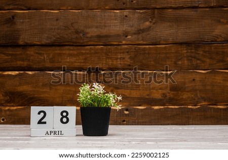 April calendar with number  28. Planner copy space on a wooden brown background. March number icon. Place for text background calendar