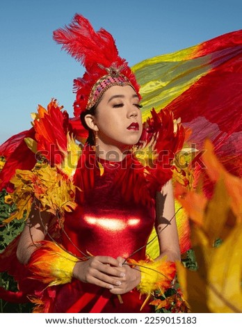 model wearing red feather pageant outfit in sunflower sunflowers field nature arizona mountainscape summer spring flowers beautiful headdress