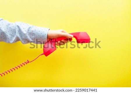Woman hand hanging up pink phone on yellow background, communication and connection concept