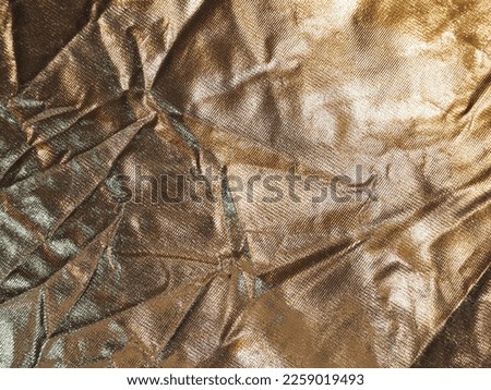 Gold reflective plastic sheet with crumpled surface for use as a background.