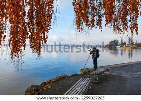 A professional photographer takes a photo of a wonderful autumn morning on the embankment of Zug Lake