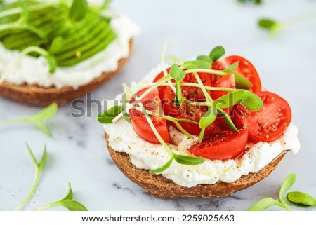 Bun toast with cream cheese, cherry tomatoes and micro greens. Healthy breakfast concept. Royalty-Free Stock Photo #2259025663