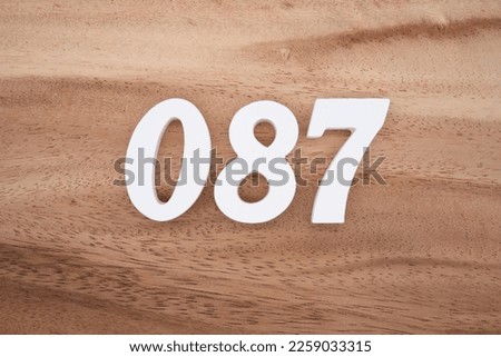 White number 087 on a brown and light brown wooden background.