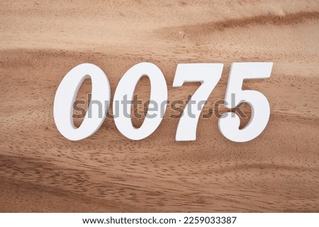White number 0075 on a brown and light brown wooden background.