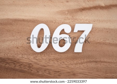White number 067 on a brown and light brown wooden background.