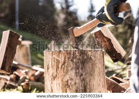 Detail of two flying pieces of wood on log with sawdust. Man is chopping wood with vintage axe. Frozen moment. Royalty-Free Stock Photo #225903364
