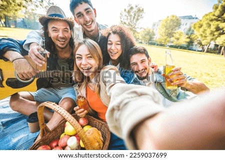 Cheerful friends having picnic party outdoors - Group of young teens taking selfie picture on summer vacation - Millenial people enjoying springtime day out - Life style concept with guys and girls