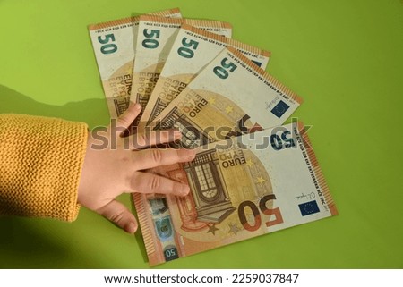 a hand of a child in front of euro bank notes Royalty-Free Stock Photo #2259037847