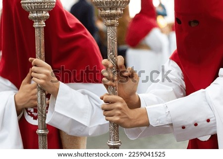 Penitents or Nazarenes leaning on the goldwork lanterns during a Holy Week procession.