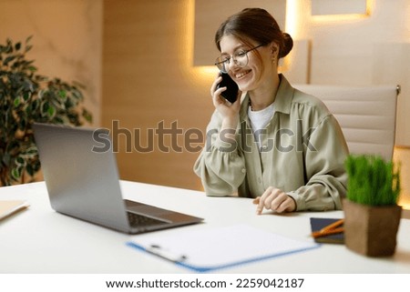 Positive office employee talking on the phone, cheerful conversation in the workplace.