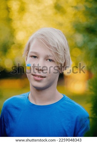 Portrait of a Ukrainian boy with a face painted with the colors of the Ukrainian flag.