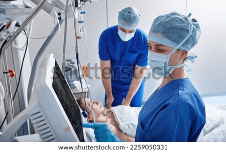 Nurses in intensive care unit of hospital checking vitals of hospitalized female patient. ICU Royalty-Free Stock Photo #2259050331