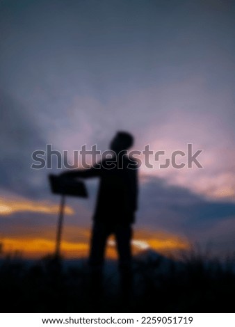 Photo of a climber who made it to the top of the mountain on a blurred background