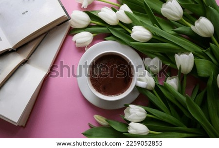 Cup of coffee among arranged bouquet white tulips top view