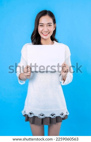 Your text here. Young excited woman holding empty blank board. Colorful studio portrait with light blue background. Woman holding blank empty banner pointing finger to one self smiling happy and proud