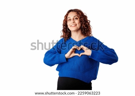 Cute millennial woman wearing sweater standing isolated over white background making a heart gesture with her fingers in front of her chest showing her love. With love, you are not alone. I love you.