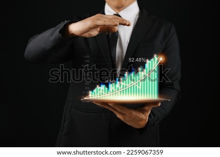 Businessman holding tablet showing realistic hologram increasing chart statistics with upward arrow, business growth concept, profitable investment, strategy planning, stock market.