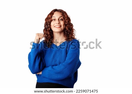Young woman smiling confident wearing blue knitted sweater standing isolated over white background smiling pointing back finger empty space. Happy face looking and pointing to the side with thumb up.