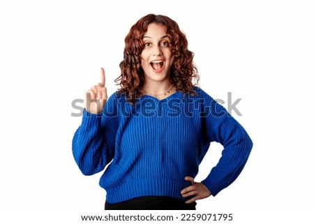 Happy woman wearing blue knitted sweater standing isolated over white background pointing finger up with successful idea. Excited and happy. Number one. Surprised woman with opened mouth.
