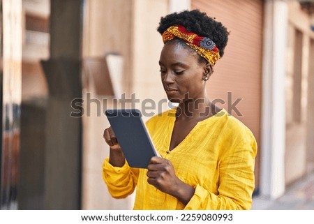 Young african american woman smiling confident using touchpad at street Royalty-Free Stock Photo #2259080993