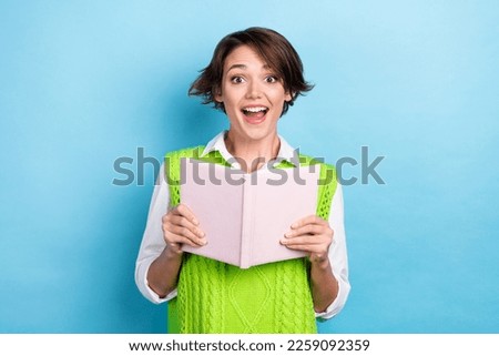 Photo of surprised funny young bookworm shock wear green knitted vest shirt hold diary surprised story moment isolated on blue color background