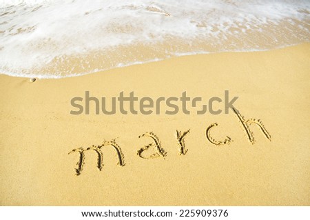 March - written in sand on beach texture - soft wave of the ocean