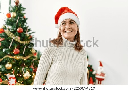 Middle age caucasian woman smiling confident standing by christmas tree at home