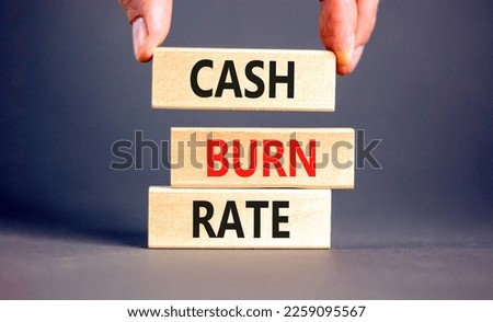 Cash burn rate symbol. Concept words Cash burn rate on wooden blocks on a beautiful grey table grey background. Businessman hand. Business cash burn rate concept. Copy space.