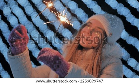 Young girl posing with sparklers against the background of New Year's daisies.