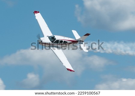 Small propeller plane flying with smoke at an airshow in the USA.  Royalty-Free Stock Photo #2259100567