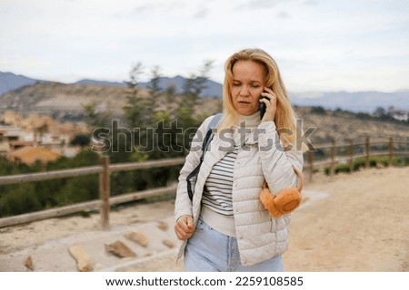A tourist woman communicates on a mobile phone against the background of nature