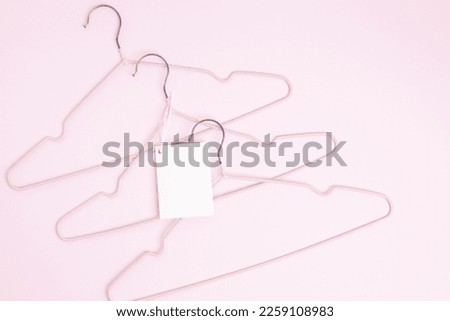 Creative flat lay hangers with white paper label pink background. Clothing tag, label blank mockup template. Sale discount store promo shopping concept. Top view. Copy space