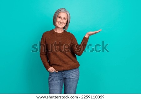 Portrait of cheerful lady toothy smile arm palm hold empty space offer isolated on emerald color background