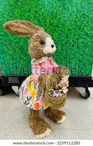 
Easter bunny girl in a pink dress on a green background with a basket of flowers , a symbol of the Easter holiday