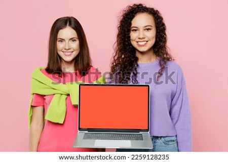 Young two friends smiling happy IT women 20s wear green purple shirts together hold use work on laptop pc computer with blank screen workspace area isolated on pastel plain light pink color background