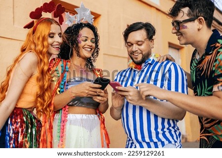 Brazilian Carnival. Group of friends celebrating carnival party using smartphones Royalty-Free Stock Photo #2259129261