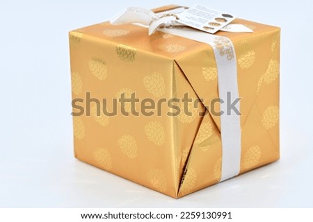 Golden gift box with a white ribbon and tag.
