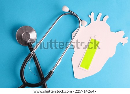 Paper cut Anatomical heart with full battery level, stethoscope on a blue background. Healthy heart concept